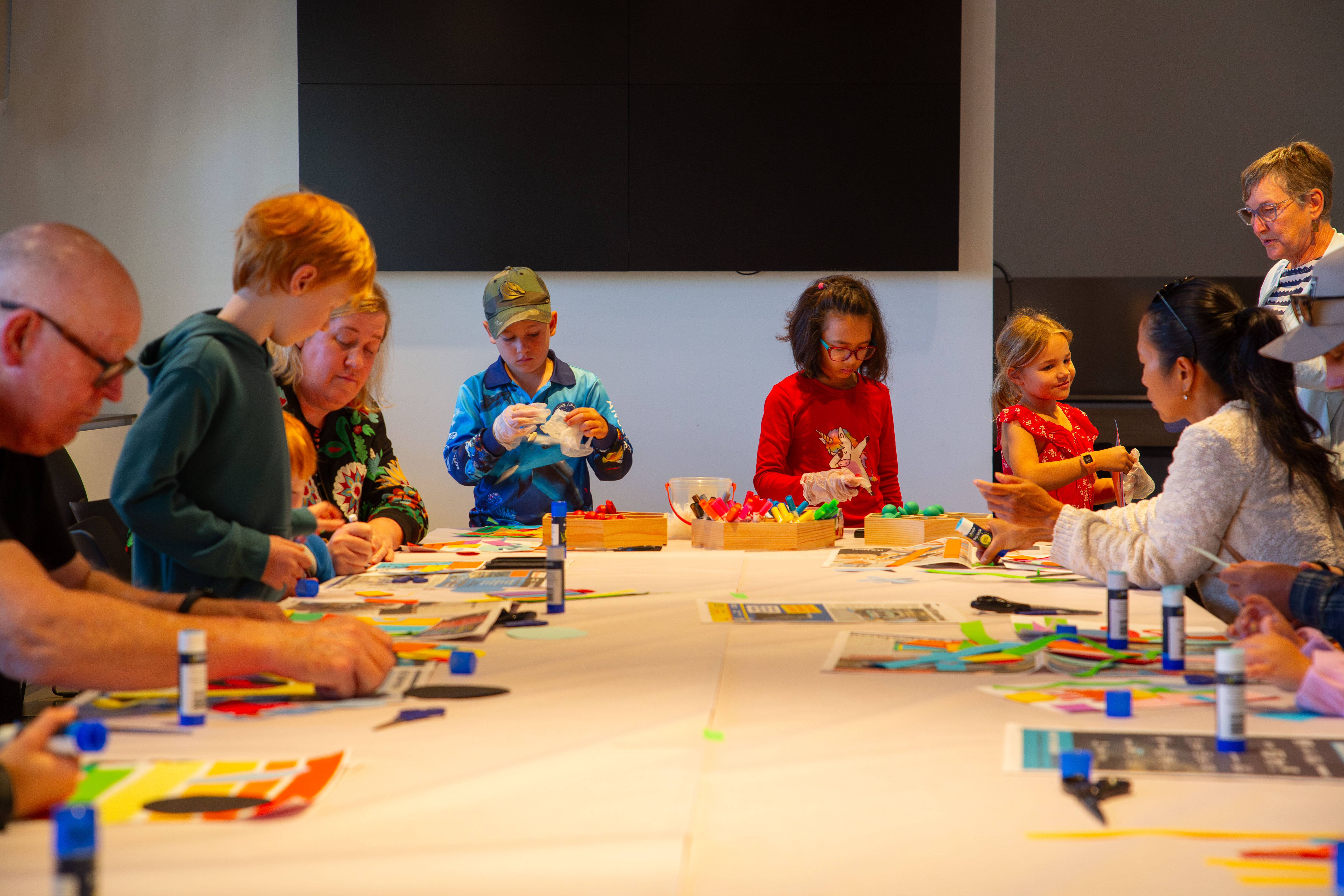 Families creating artworks together in a classroom at RMOA school holidays. 